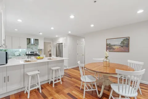 a kitchen with stainless steel appliances granite countertop a dining table chairs and white cabinets