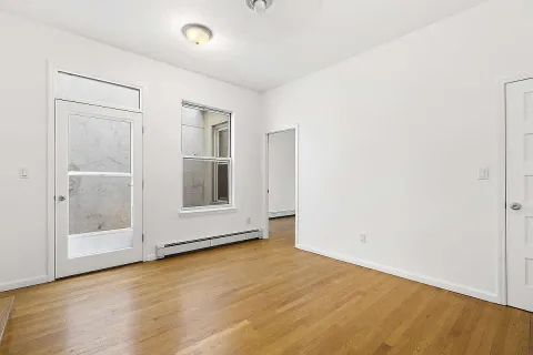 a view of an empty room with wooden floor and a window