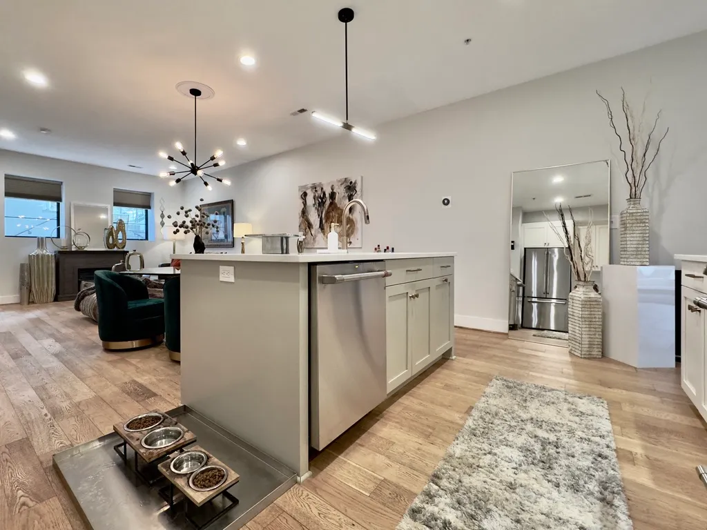 a kitchen with stainless steel appliances granite countertop a sink dishwasher a stove a refrigerator and a dining table with wooden floor