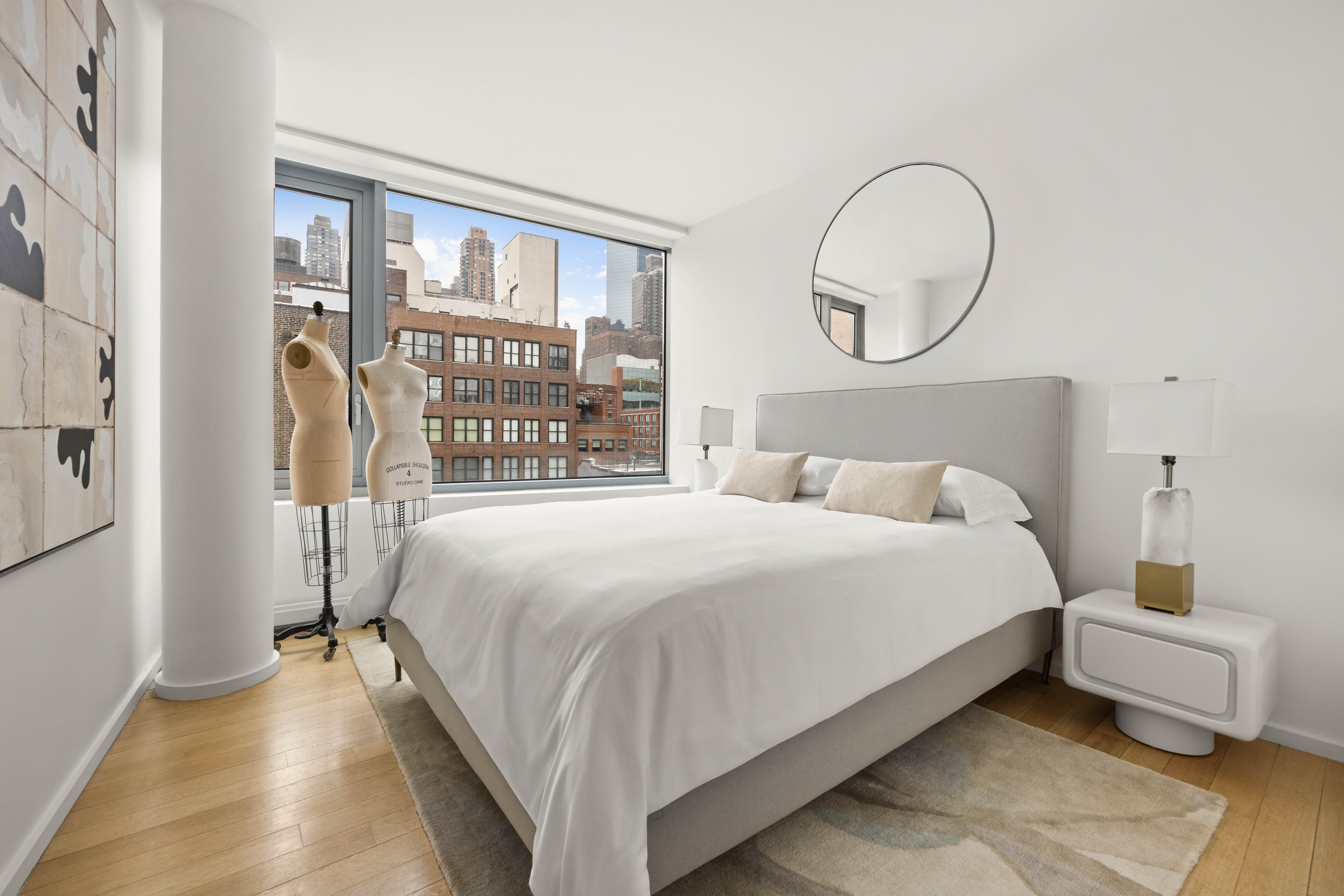 425 West 53rd Street, Unit 604 Manhattan, NY 10019 - Photo 9 of 12 a bedroom with a bed a mirror and a large window with outer view