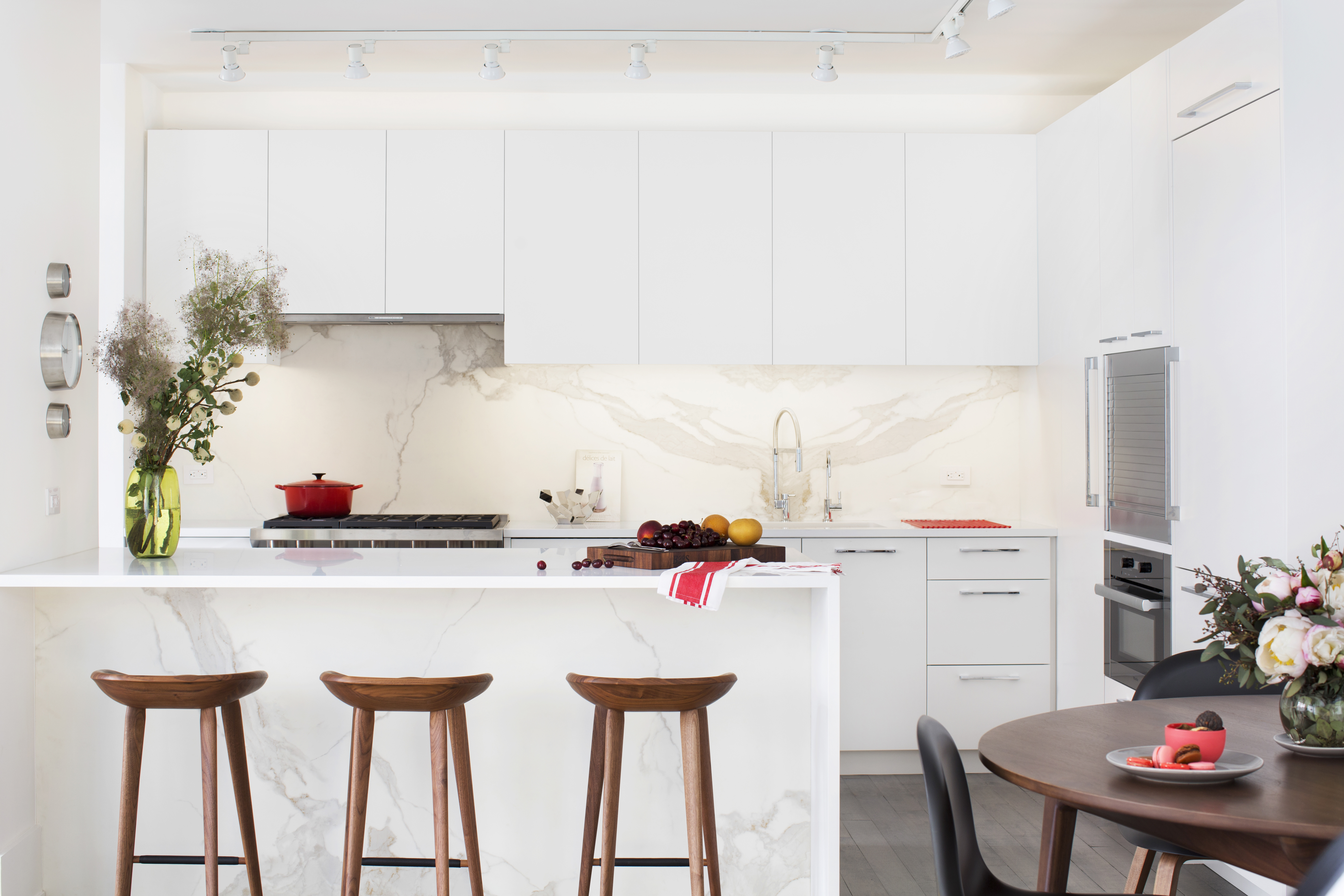 a kitchen with stainless steel appliances a white table and chairs in it