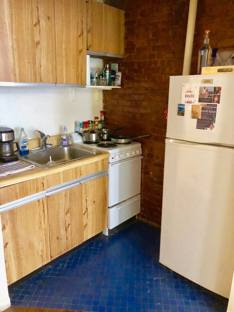344 East 61st Street, Unit 7 Manhattan, NY 10065 - Photo 3 of 4 a kitchen with stainless steel appliances a stove a sink a refrigerator wooden floor and cabinets