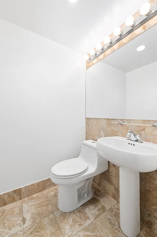 160 West 66th Street, Unit 17E Manhattan, NY 10023 - Photo 6 of 13 a bathroom with a sink a toilet and mirror