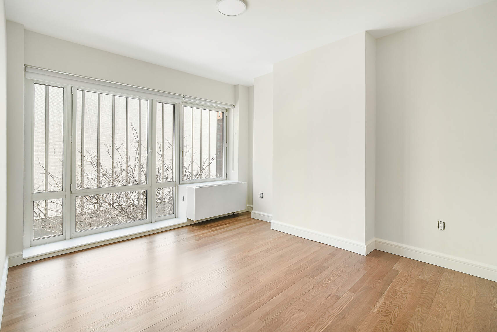 454 West 54th Street, Unit 3A Manhattan, NY 10019 - Photo 9 of 13 an empty room with wooden floor and windows