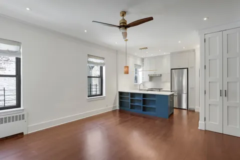 a kitchen with stainless steel appliances granite countertop a refrigerator a sink dishwasher a stove and white countertops with wooden floor