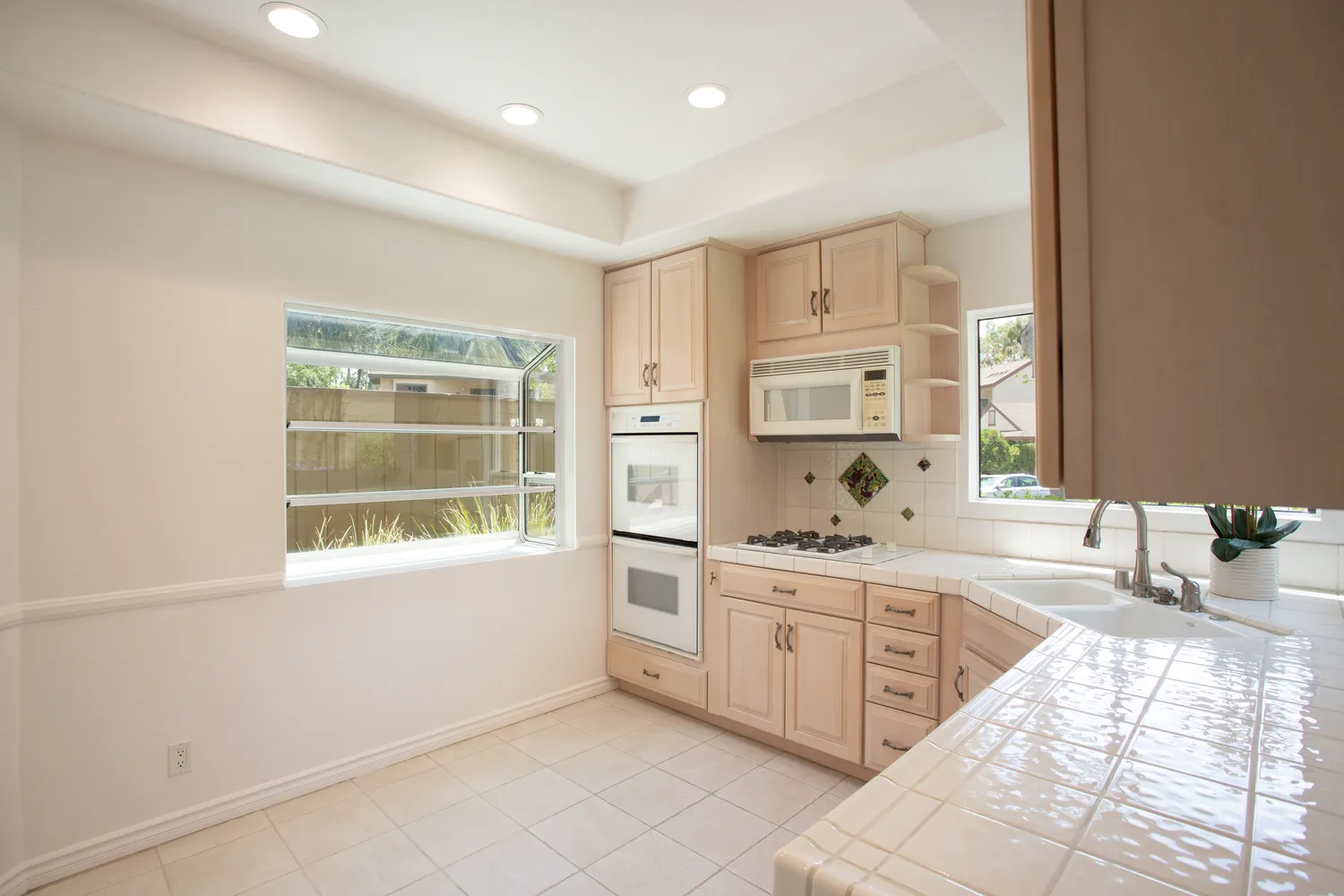a large white kitchen with granite countertop a large window and white stainless steel appliances