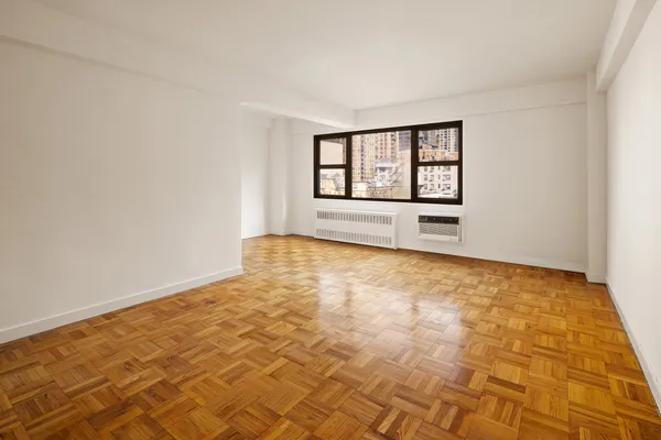 a view of an empty room with window and wooden floor