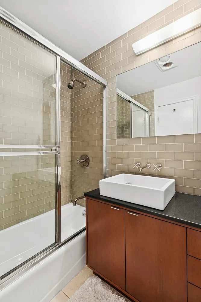 a bathroom with a sink and mirror with bathtub