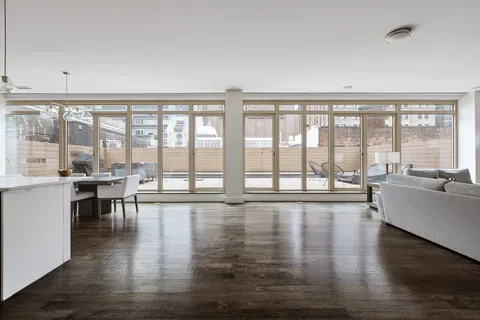 a living room with furniture large windows and wooden floor