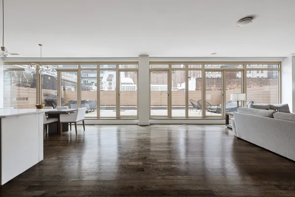a living room with furniture large windows and wooden floor