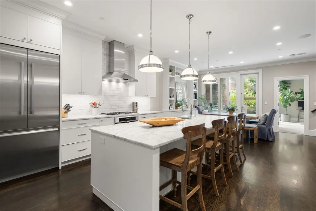 a kitchen with stainless steel appliances kitchen island granite countertop a table chairs and a chandelier