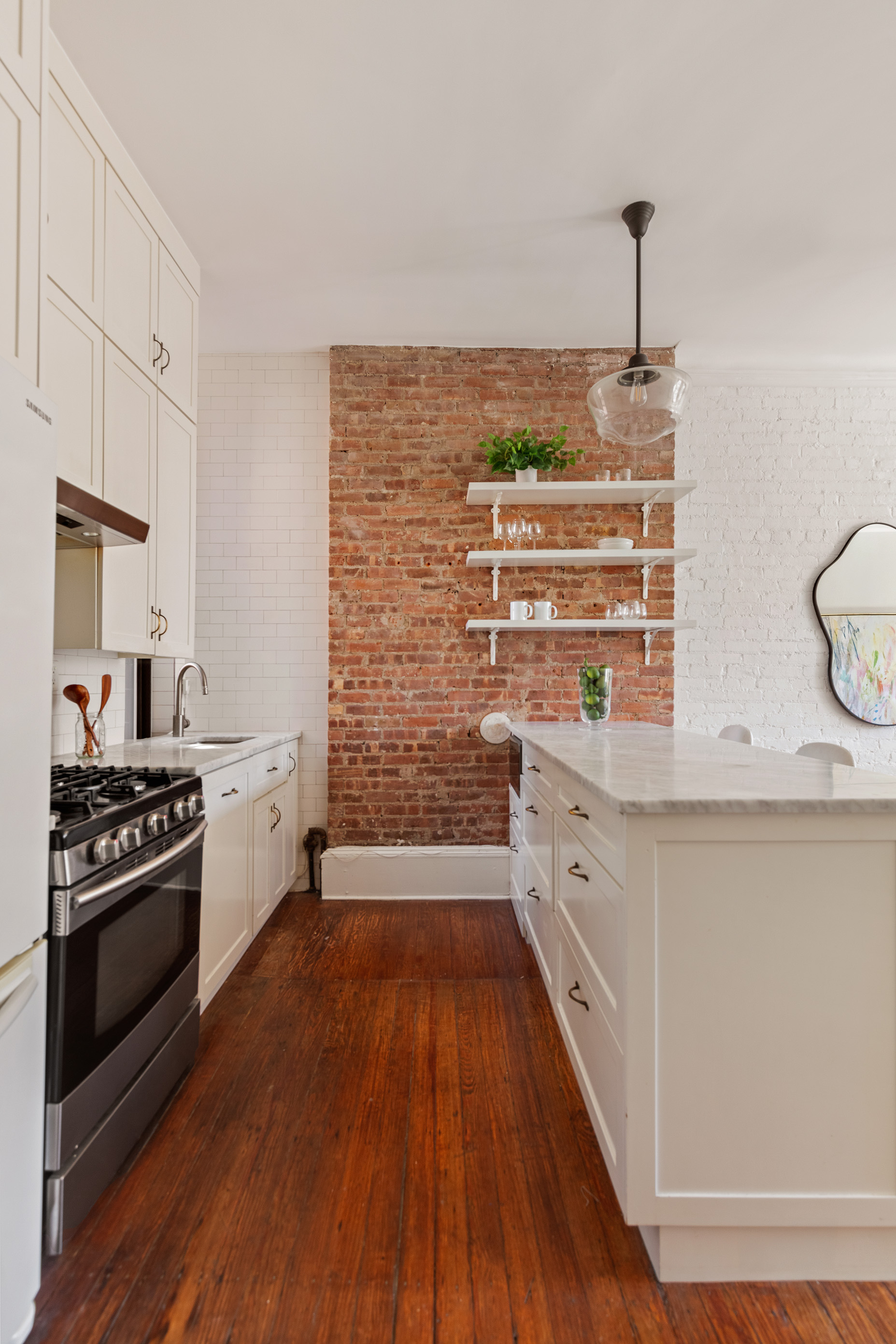 223 West 21st Street, Unit PH5M Manhattan, NY 10011 - Photo 5 of 12 a kitchen with stainless steel appliances a stove and white cabinets with wooden floor