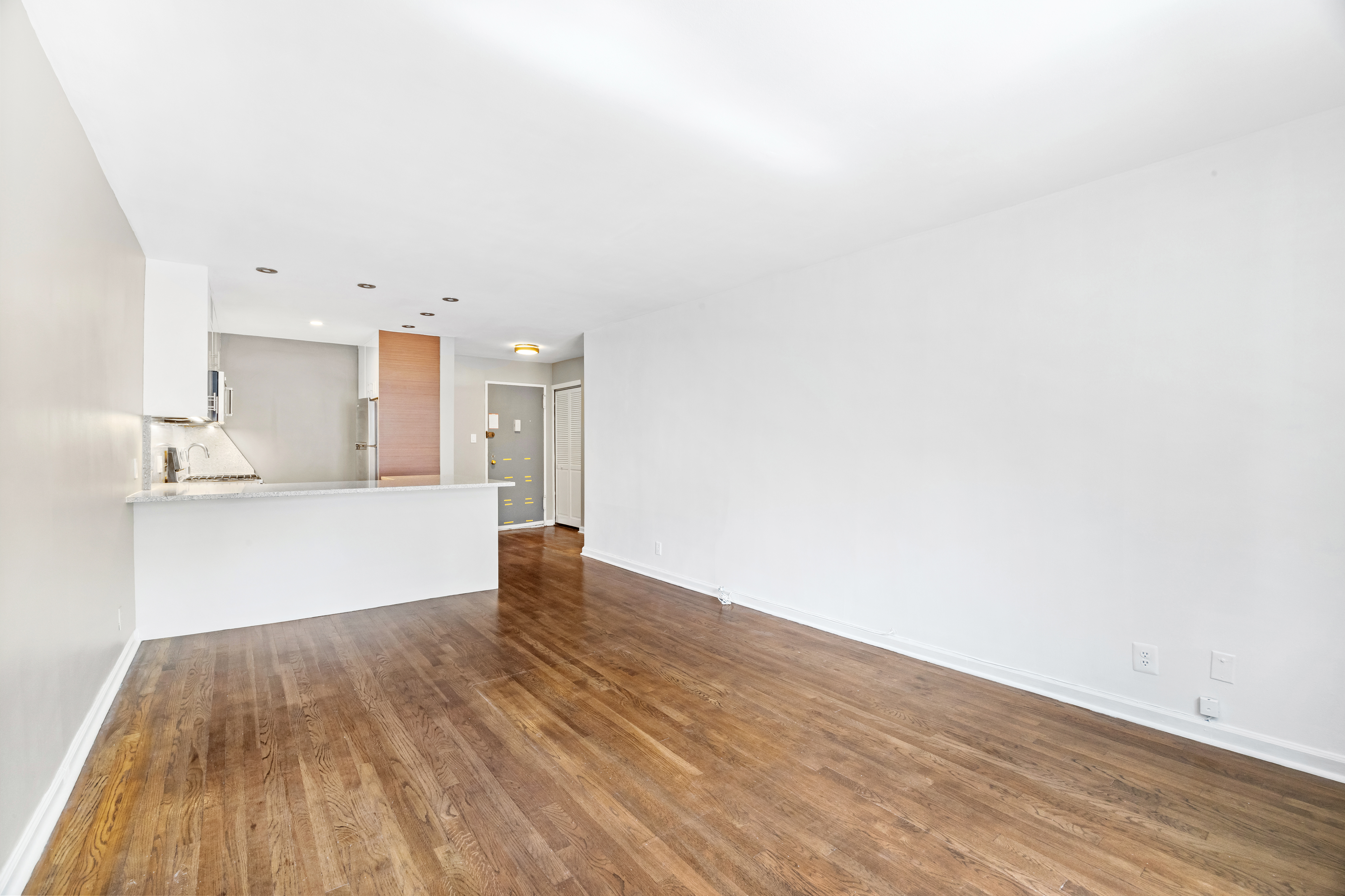 140 7th Avenue, Unit 4J Manhattan, NY 10011 - Photo 3 of 8 a view of kitchen and empty room with wooden floor
