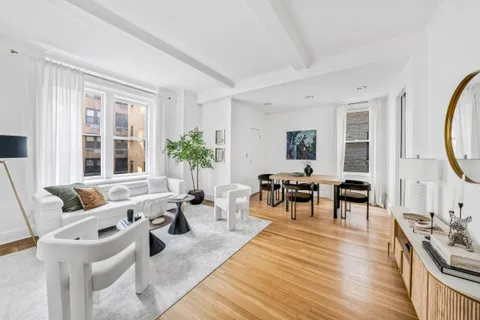 a living room with furniture large window and wooden floor