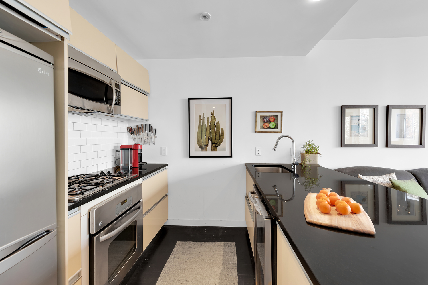 29 Montrose Avenue, Unit 4B Brooklyn, NY 11206 - Photo 3 of 6 a kitchen with stainless steel appliances a stove a microwave a refrigerator white cabinets and couches