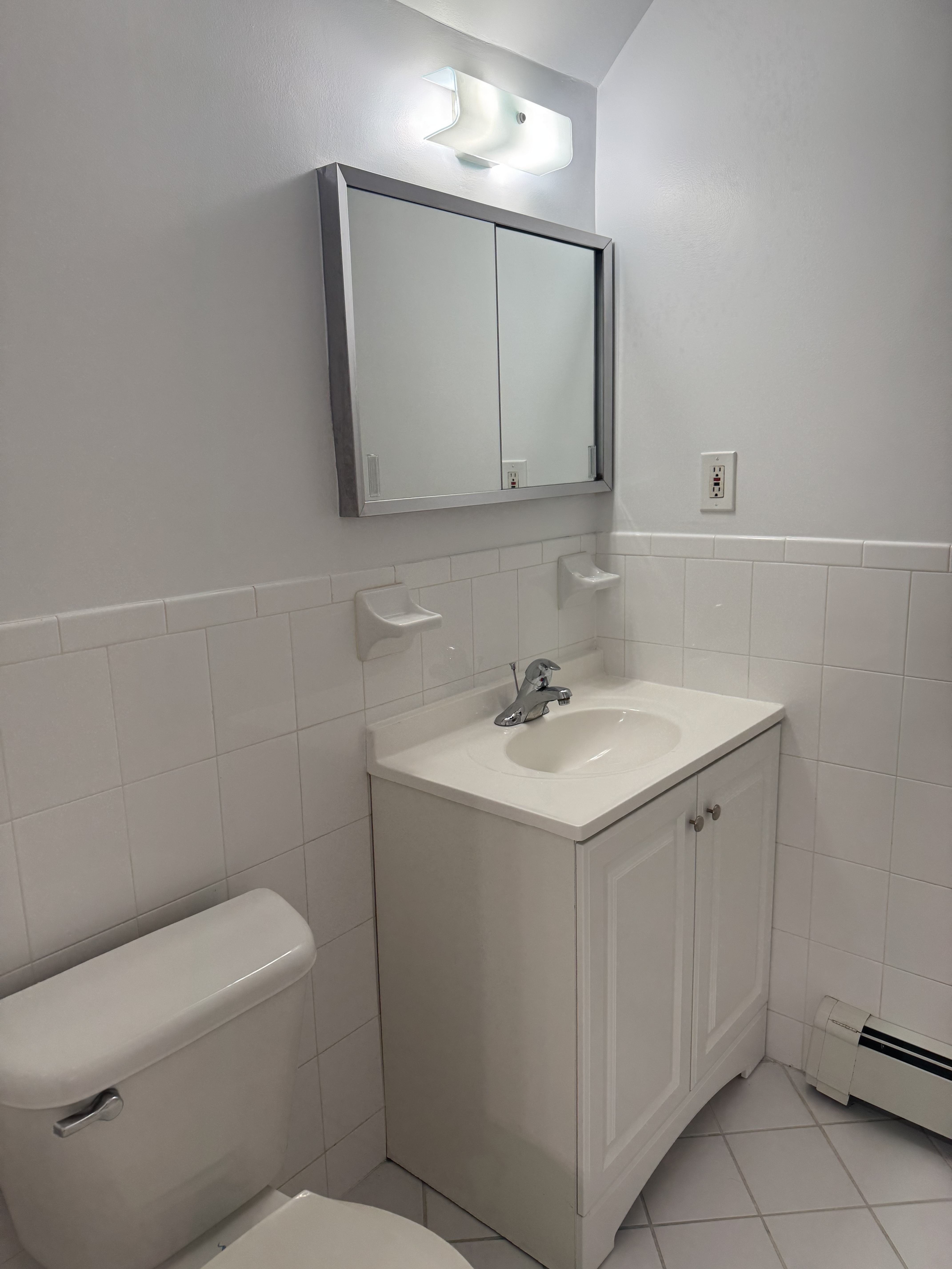 39-46 59th Street, Unit 1 Queens, NY 11377 - Photo 6 of 6 a bathroom with a sink a toilet and mirror