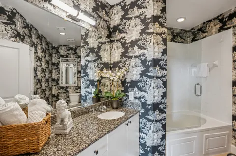a bathroom with a granite countertop sink a mirror and shower