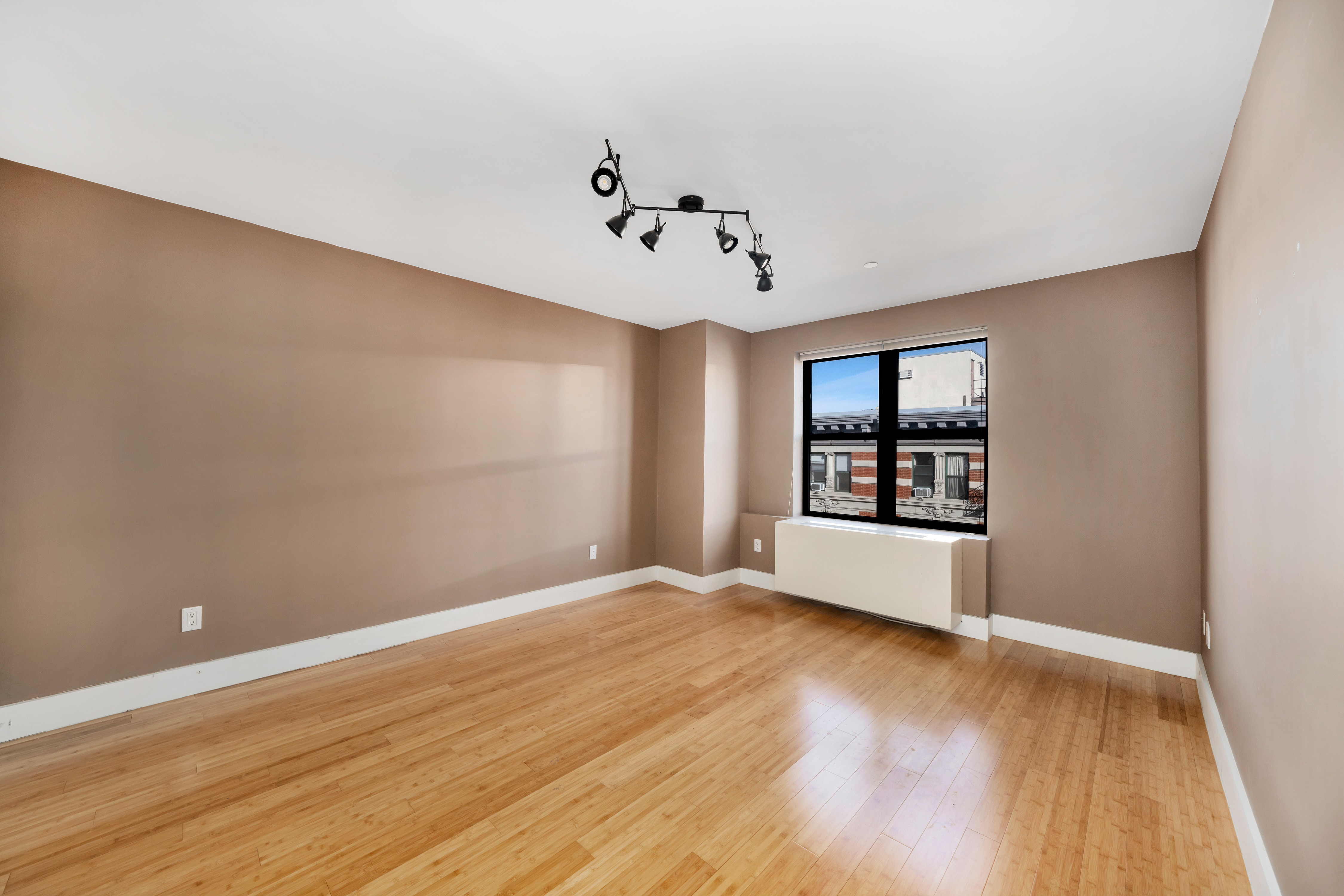 234 West 148th Street, Unit 5D Manhattan, NY 10039 - Photo 4 of 16 a view of an empty room with a window and wooden floor