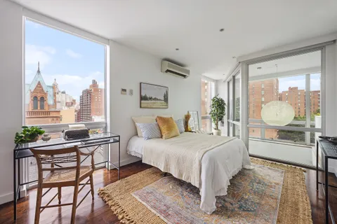 a bedroom with a bed and large windows