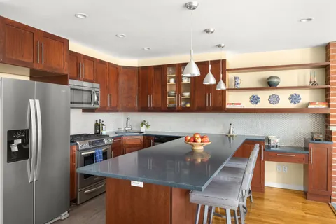 a kitchen with stainless steel appliances granite countertop a dining table chairs refrigerator and sink