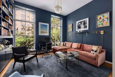 a living room with furniture a bookshelf and a window