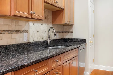 a kitchen with granite countertop a sink a stove and cabinets