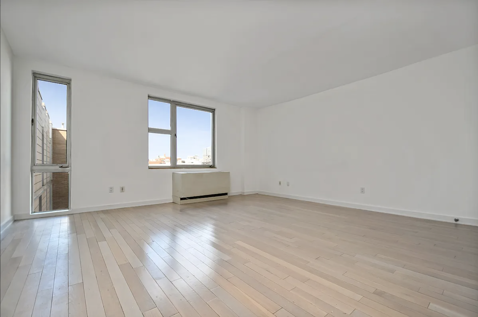 250 Bedford Avenue, Unit 129405 Brooklyn, NY 11249 - Photo 3 of 8 a view of an empty room with wooden floor and a window