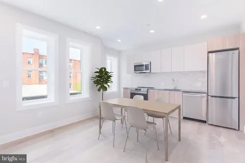 a kitchen with stainless steel appliances granite countertop a refrigerator a sink a stove a dining table and chairs