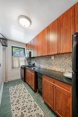 469 West 141st Street Manhattan, NY 10031 - Photo 6 of 14 a kitchen with stainless steel appliances granite countertop wooden cabinets a sink dishwasher a stove and a refrigerator with wooden floor