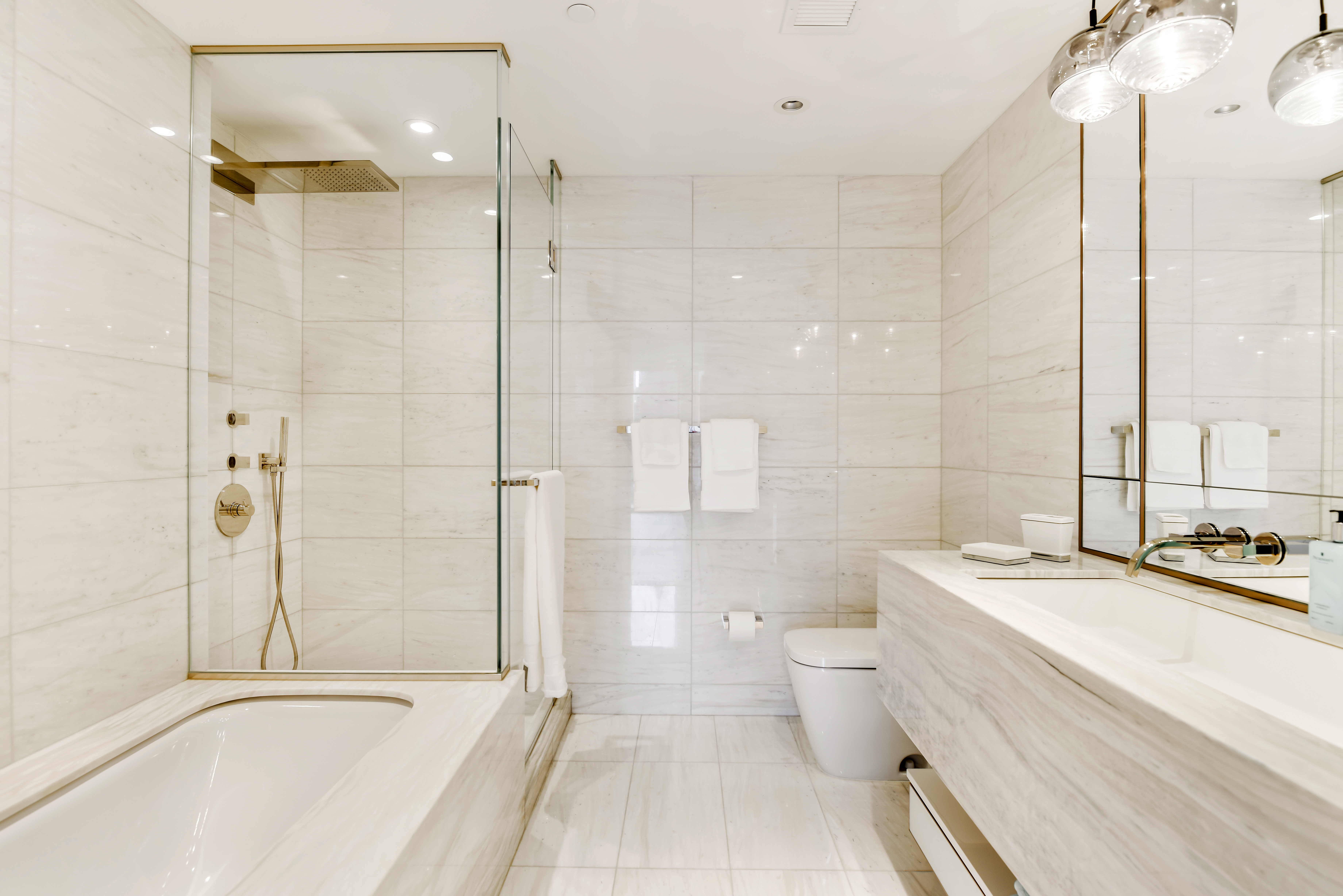135 West 52nd Street, Unit 23C Manhattan, NY 10019 - Photo 9 of 19 a bathroom with a granite countertop sink a toilet and shower