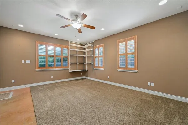 an empty room with windows and ceiling fan