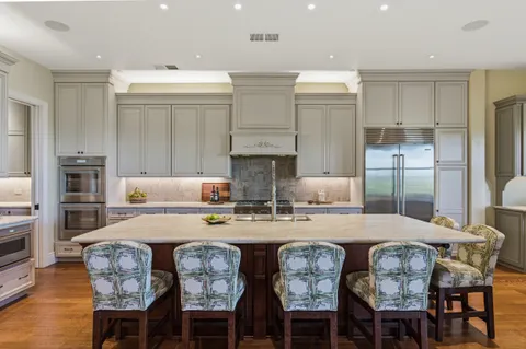 a kitchen with stainless steel appliances granite countertop a table chairs stove and refrigerator