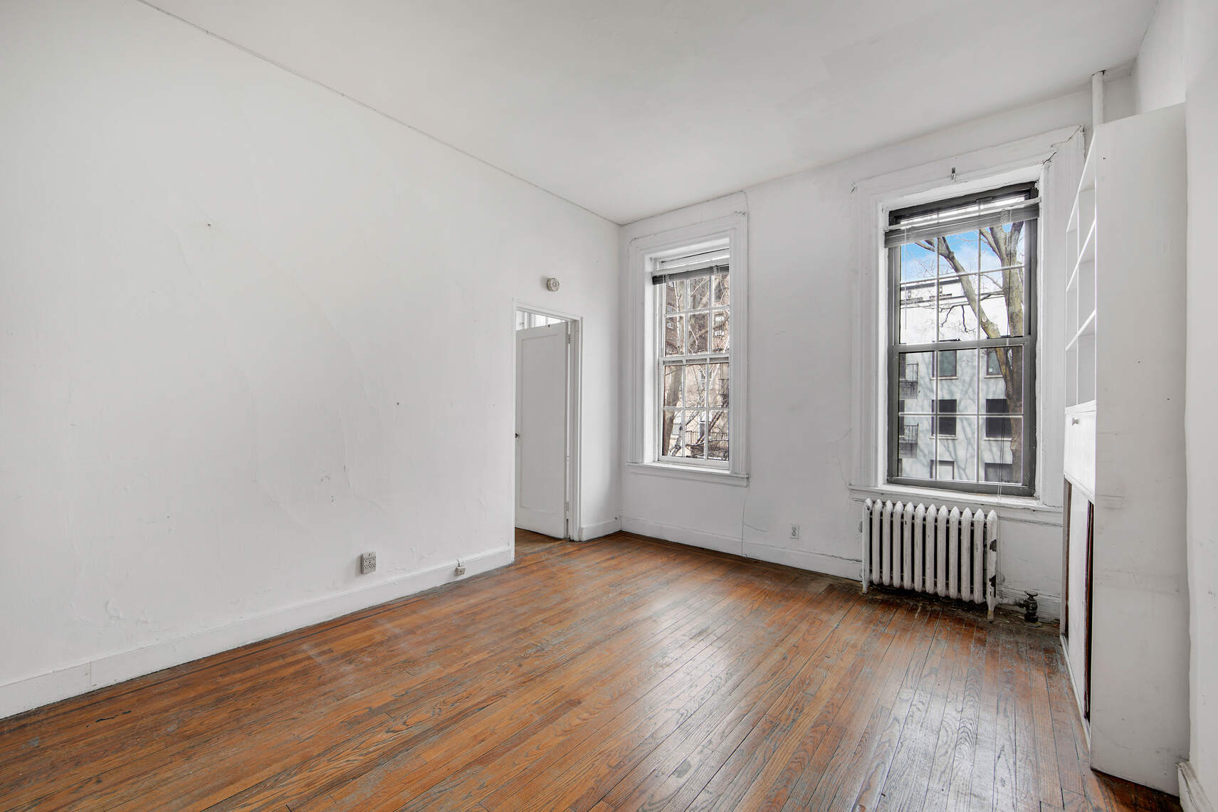 337 East 18th Street Manhattan, NY 10003 - Photo 11 of 16 an empty room with wooden floor and windows