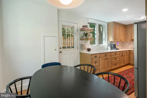 a kitchen with stainless steel appliances a sink a stove a refrigerator cabinets and a dining table