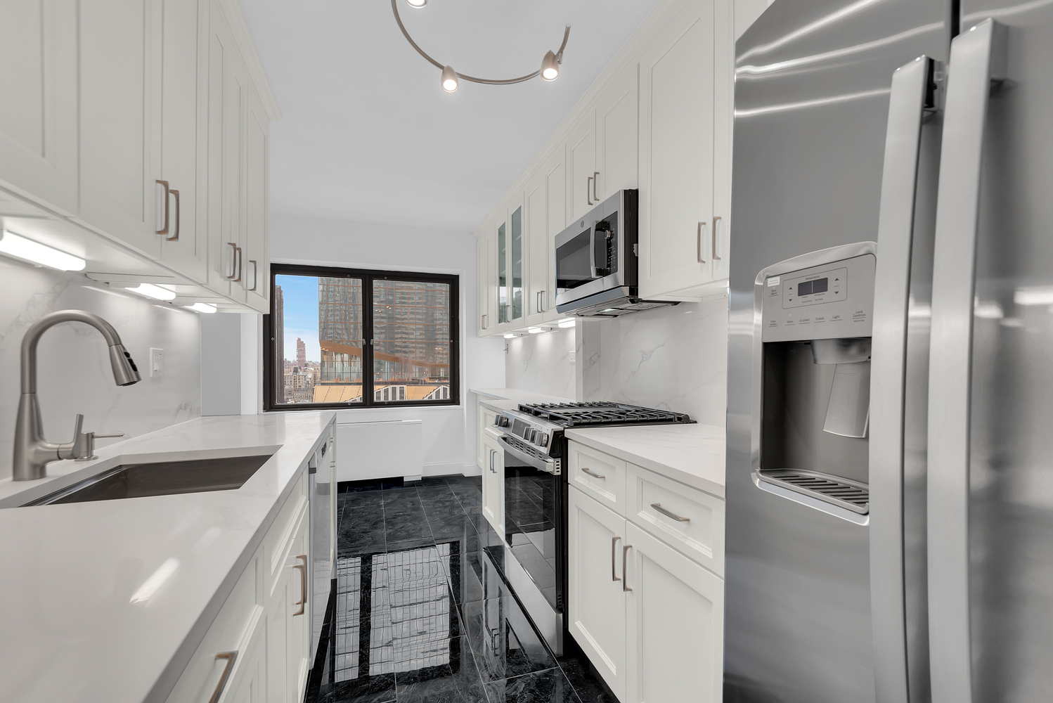 20 West 64th Street, Unit 20K Manhattan, NY 10023 - Photo 5 of 17 a kitchen with white cabinets and stainless steel appliances