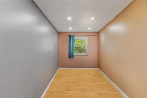 an empty room with wooden floor and window