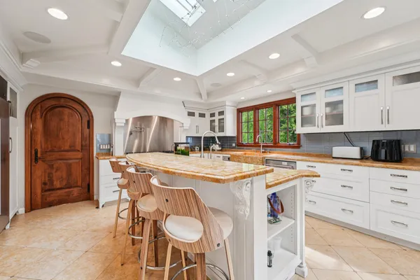a kitchen with stainless steel appliances granite countertop a stove a sink dishwasher and white cabinets with wooden floor
