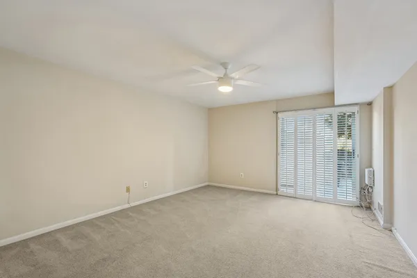 an empty room with a ceiling fan and a window