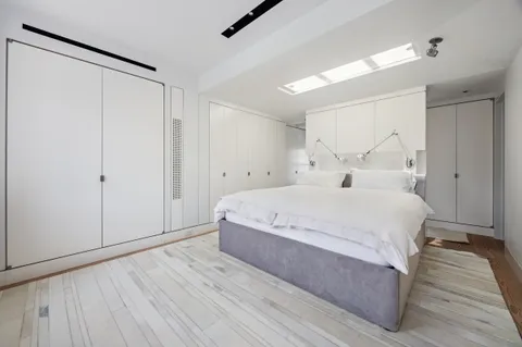 a spacious bedroom with a bed and a wooden floor