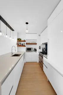 a large white kitchen with cabinets a sink and appliances