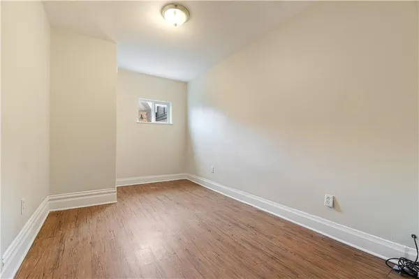 an empty room with wooden floor and window