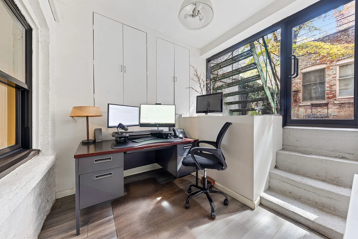a view of a workspace with furniture and a window
