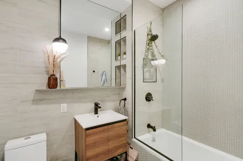 a bathroom with a tub shower sink and mirror