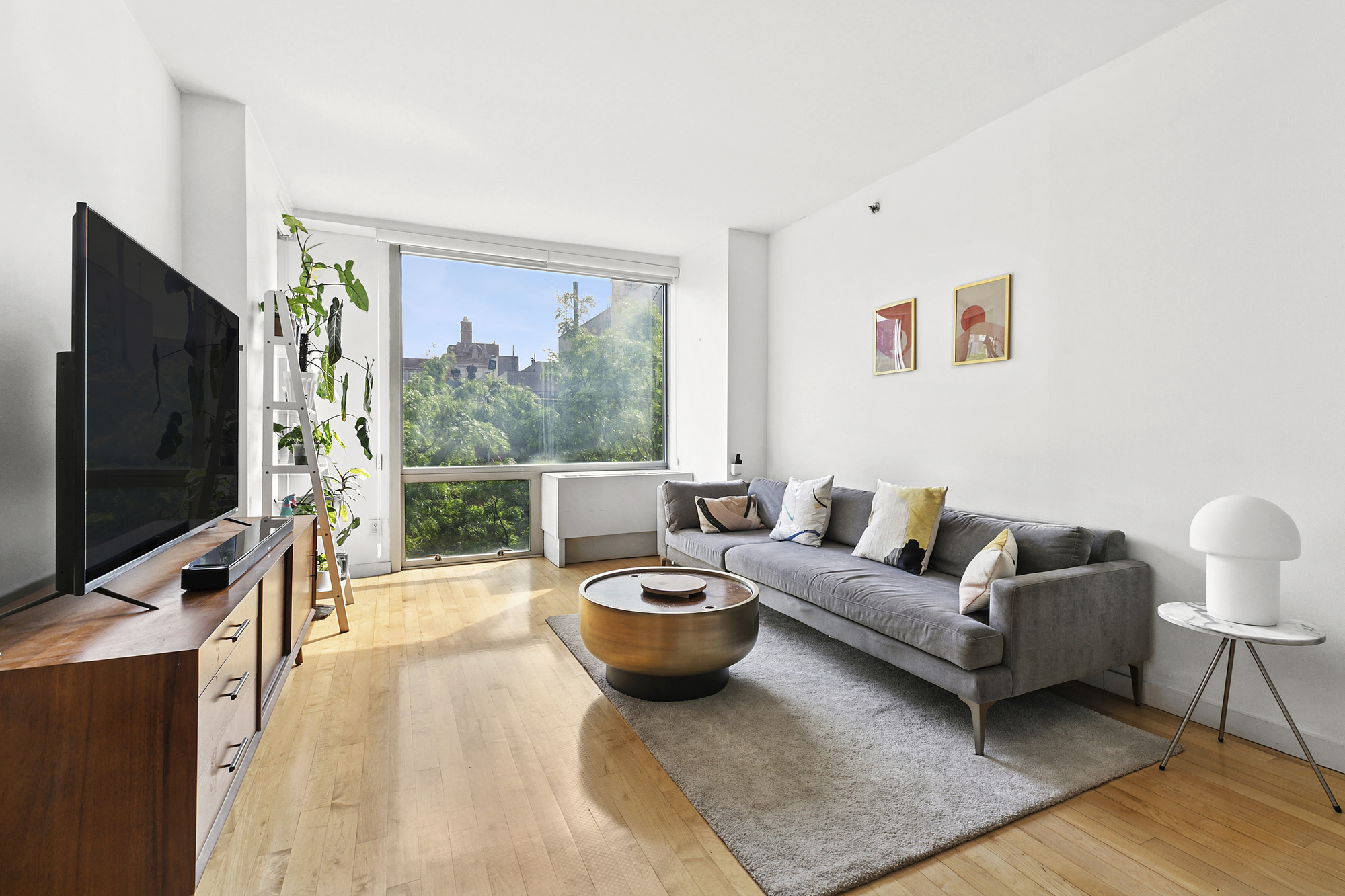 a living room with furniture a flat screen tv and a floor to ceiling window