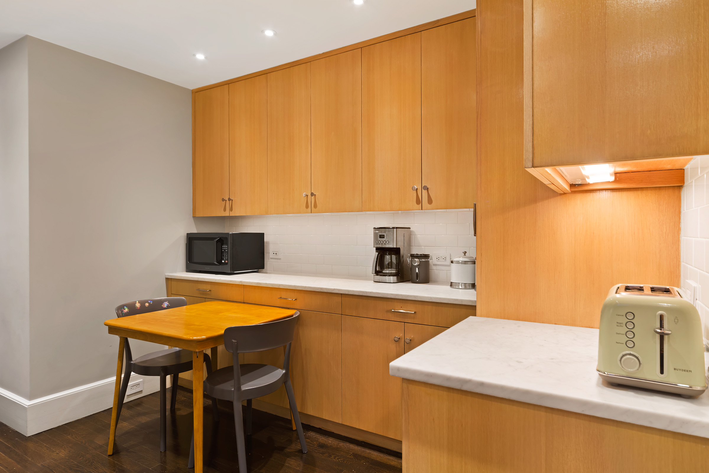 25 East 86th Street, Unit 3C Manhattan, NY 10028 - Photo 5 of 15 a kitchen with a table chairs and a refrigerator