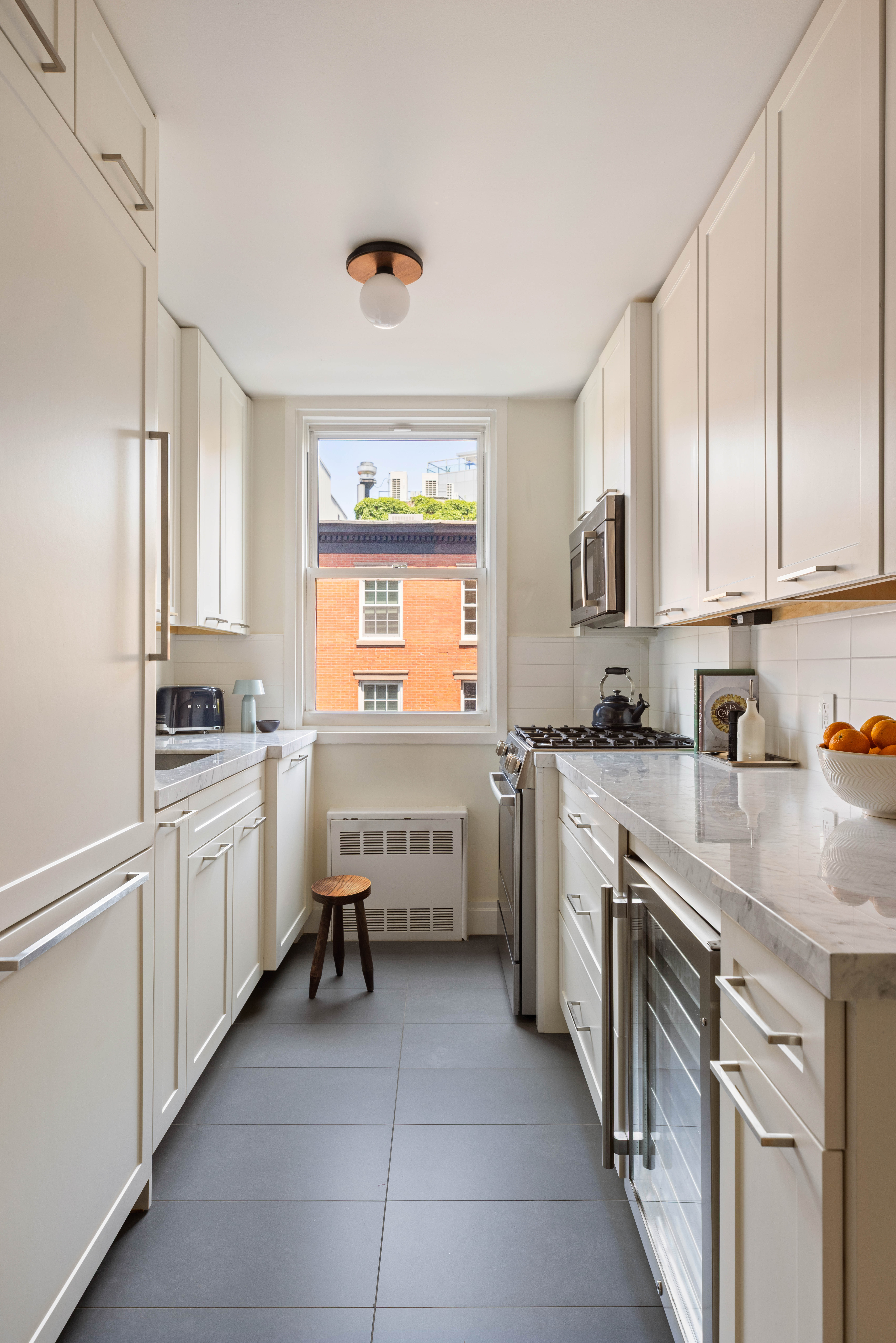 61 Jane Street, Unit 4L Manhattan, NY 10014 - Photo 3 of 11 a kitchen with white cabinets and white appliances