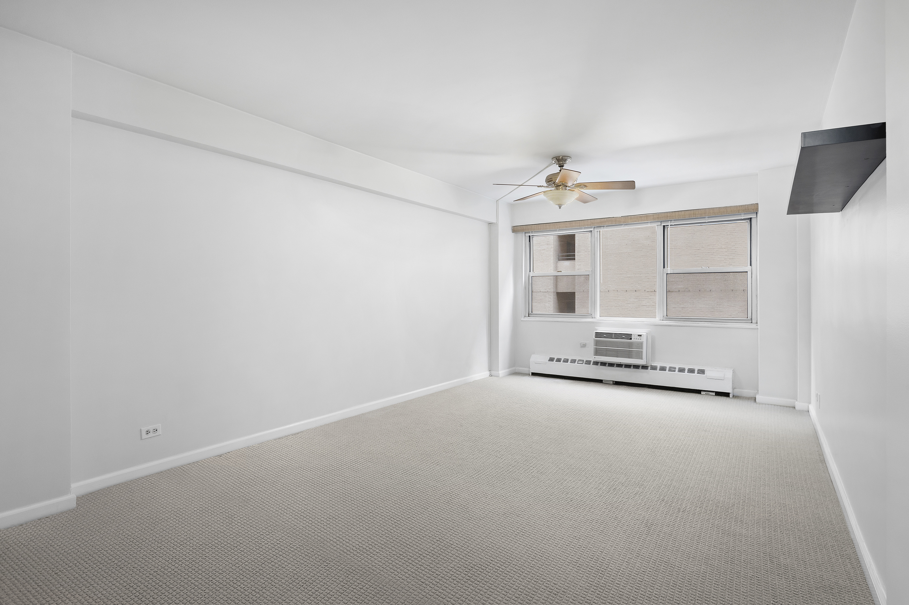 153 East 57th Street, Unit 8J Manhattan, NY 10022 - Photo 5 of 8 an empty room with chandelier fan and windows