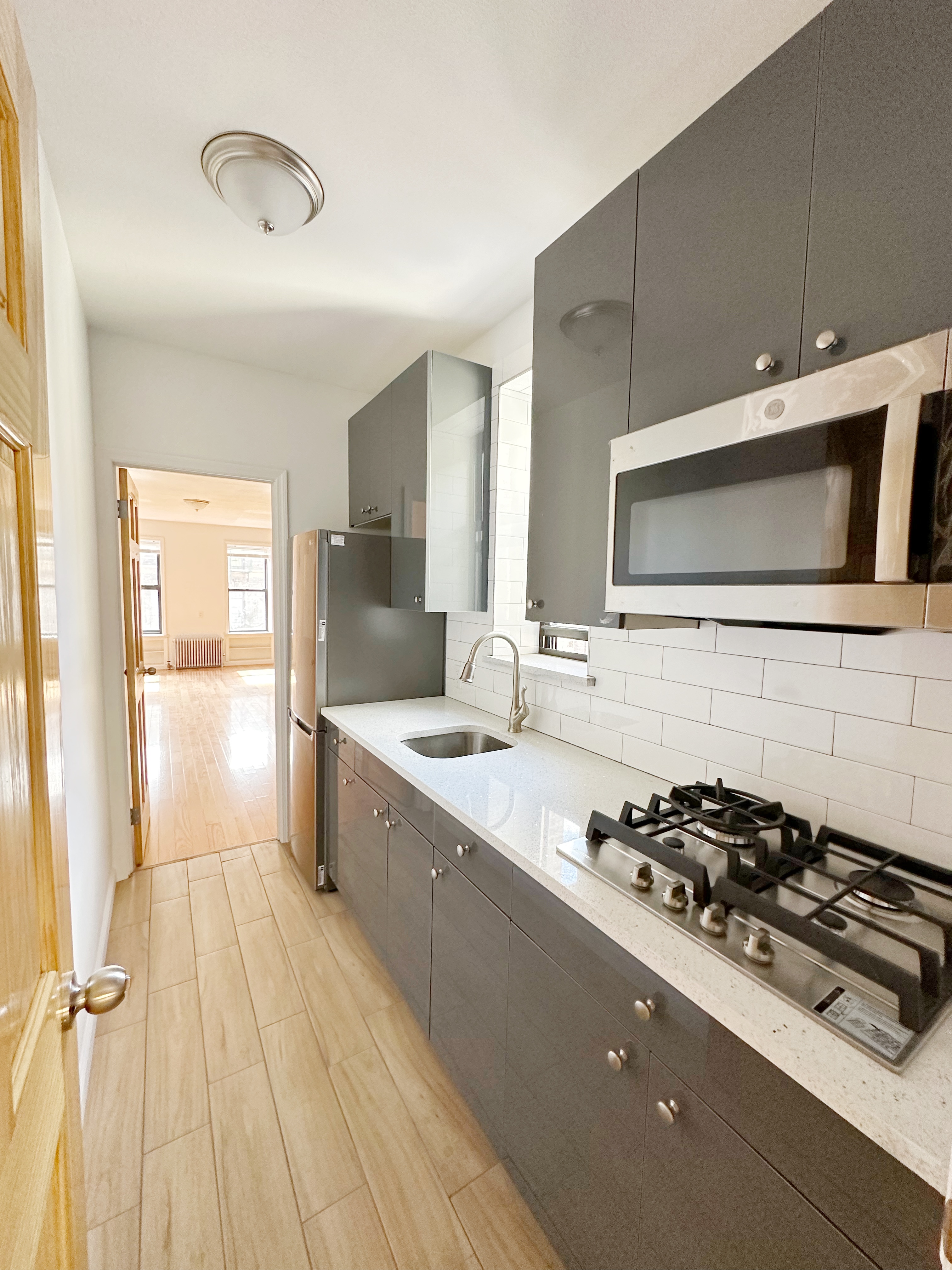 75 Madison Street, Unit 9 Manhattan, NY 10002 - Photo 5 of 6 a kitchen with a stove a sink and a microwave