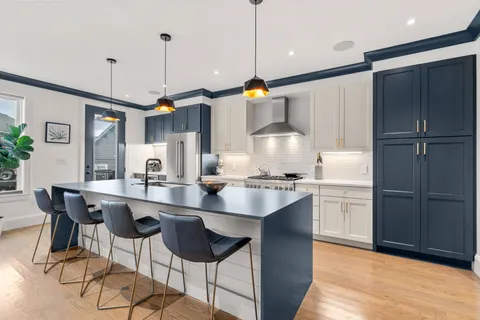 a kitchen with stainless steel appliances granite countertop a sink a stove a refrigerator and chairs