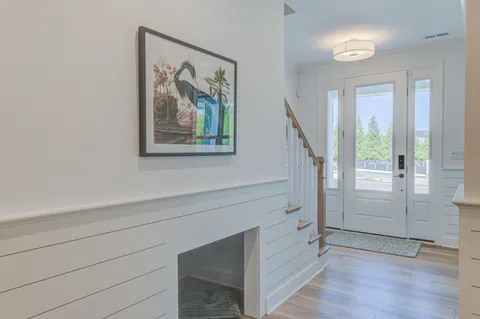 a view of hallway with window and wooden floor